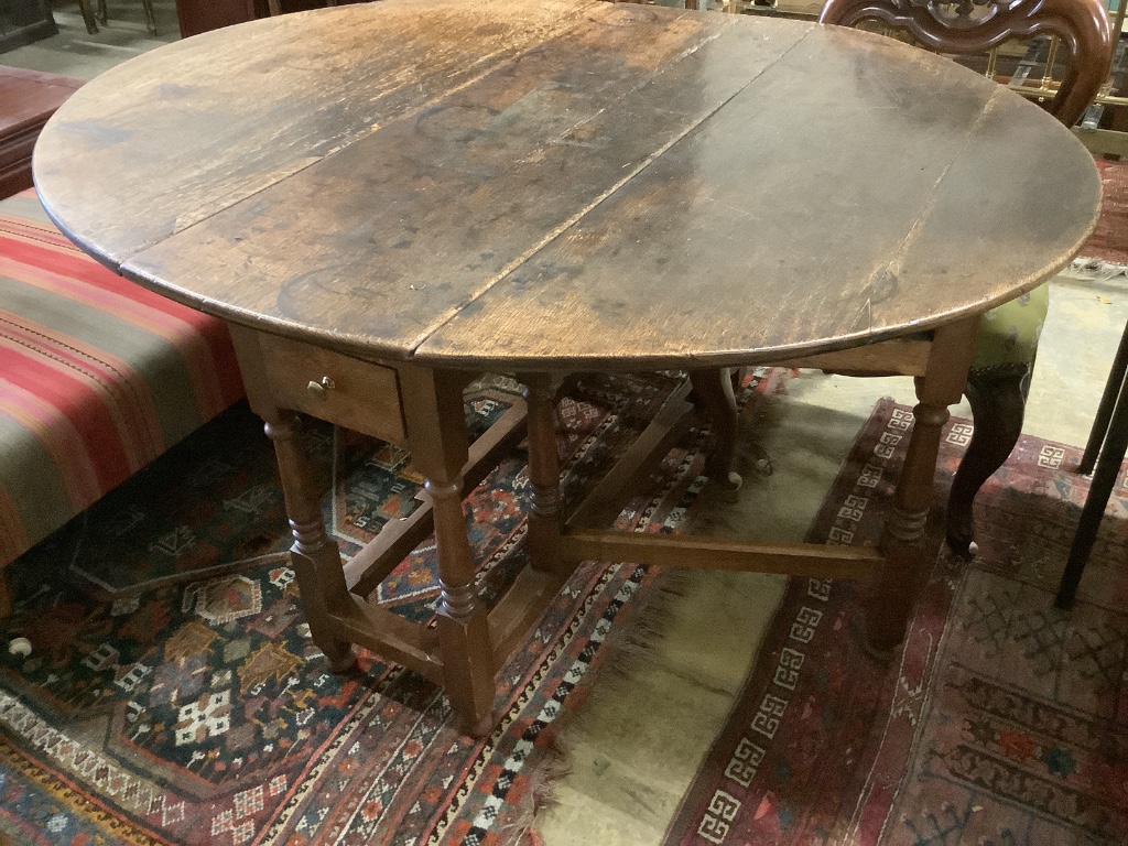 A mid 18th century oak oval topped gate leg dining table, fitted one drawer